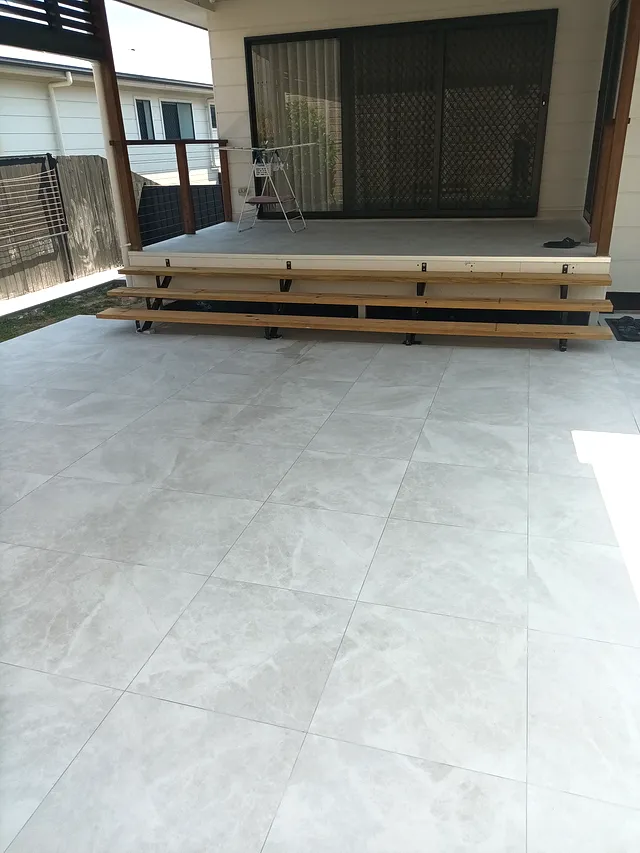 Large-format porcelain tiles on a covered outdoor patio beside a timber deck
